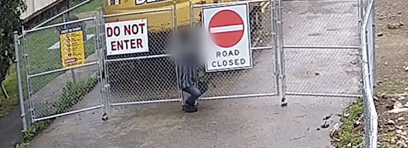 Trespasser Slips Through a Gap in Construction Site Perimeter Fencing Hero