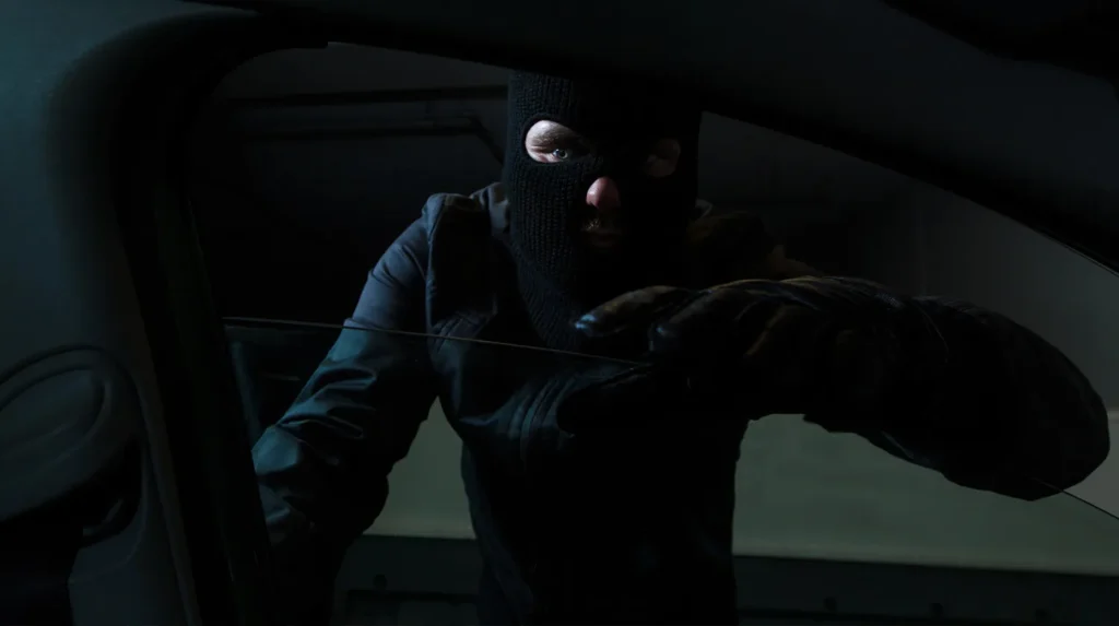 masked man looking inside vehicle: collision center theft